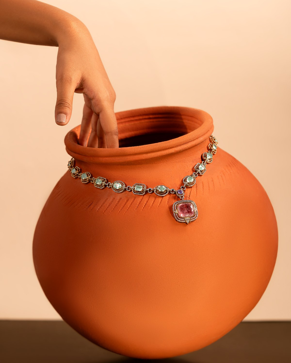 Terracotta pot styled with a gemstone necklace, product photography by Pixellery Studio